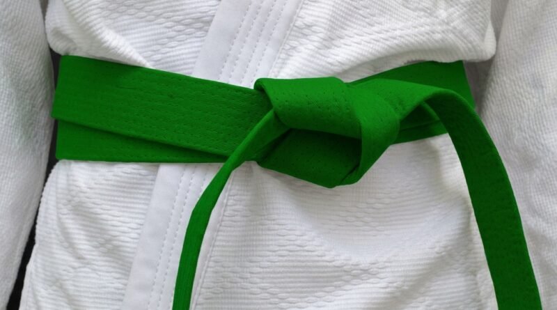 Taekwondo student wearing a green belt practicing a kick during training